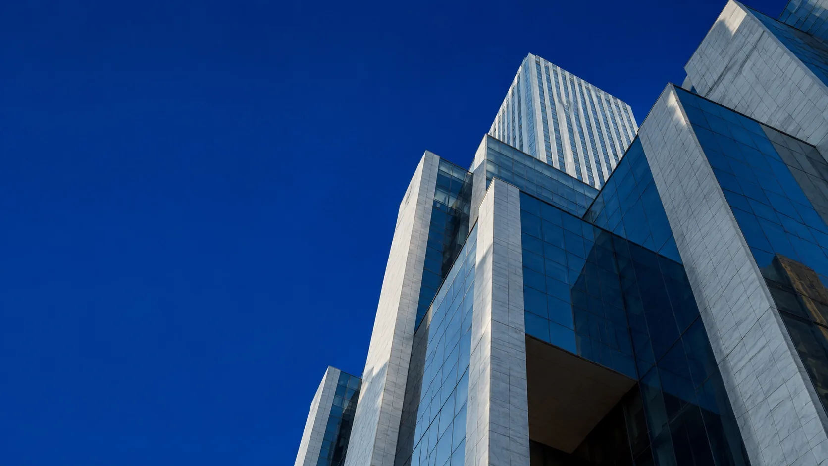 Conceptual glass and stone towers rising into a cobalt sky